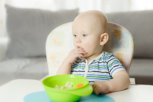 6 ヶ月の赤ちゃんが彼の手で夕食のためパスタを食べてる - 写真・画像