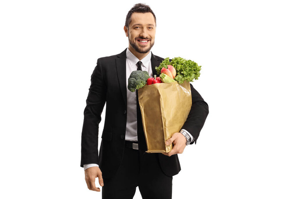 Businessman with a grocery bag smiling at camera isolated on white background - Zdjęcie, obraz