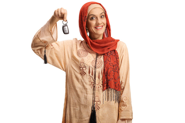 Excited muslim woman showing a car key and smiling isolated on white background - Fotoğraf, Görsel