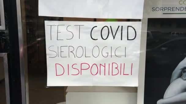 υλικό από την πινακίδα στην γυάλινη πόρτα που διαβάζει covid test serological διαθέσιμο στα ιταλικά  - Πλάνα, βίντεο