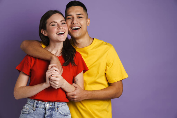 Happy beautiful couple hugging and holding hands isolated over violet background - Zdjęcie, obraz