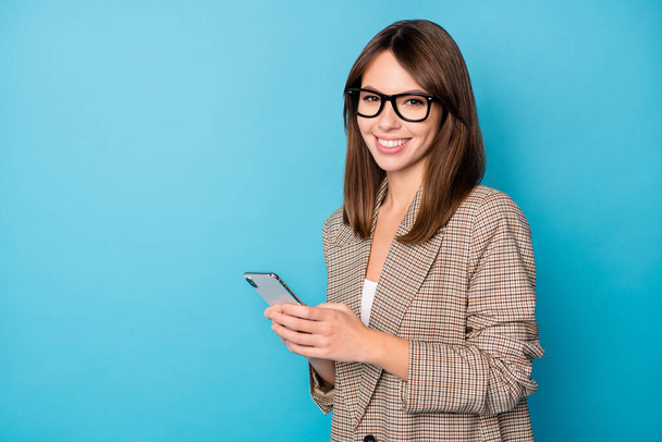 Profile photo of optimistic brunette lady look telephone wear spectacles brown jacket isolated on vivid blue background - Fotografie, Obrázek