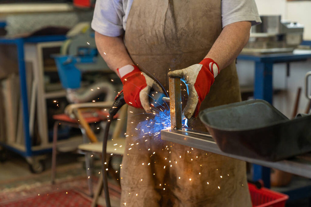 Деталь людини, що зварює сталеві рами в майстерні підробки та металообробки
 - Фото, зображення