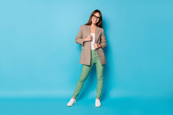 Full size photo of optimistic brunette lady stand wear spectacles brown jacket pants sneakers isolated on vivid blue background - Φωτογραφία, εικόνα