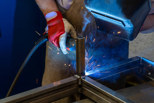 Detalle de un hombre soldando marcos de acero en un taller de falsificación y metal - Foto, imagen