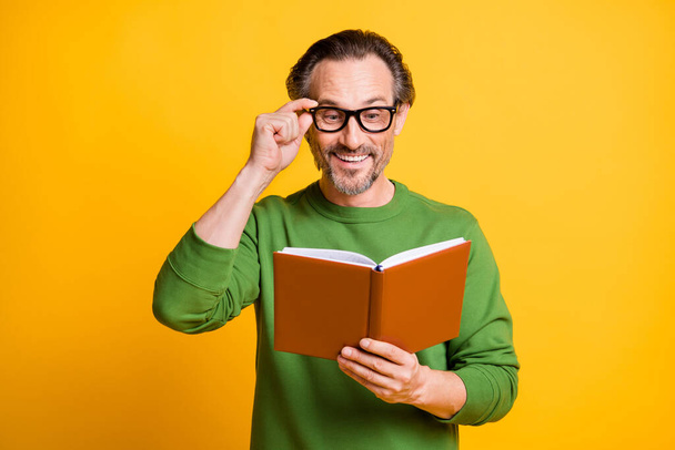 Photo of man hold diary read adjust specs curious wear green sweater isolated yellow color background - Φωτογραφία, εικόνα