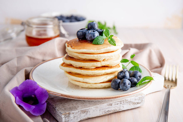 Homemade pancakes with blueberries and powdered sugar on the white table - Foto, Imagen