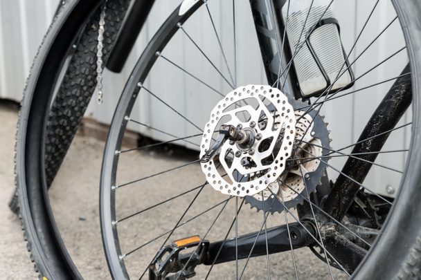Détail en gros plan vélo en fibre de carbone noir démonté avec roue et pneu enlevés après perforation ou accident à la station de réparation à l'extérieur. Pièces de vélo sport léger sur rue en ville - Photo, image