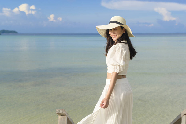 A happy beautiful woman in white dress enjoying and relaxing on the beach, Summer and holidays concept - Foto, afbeelding