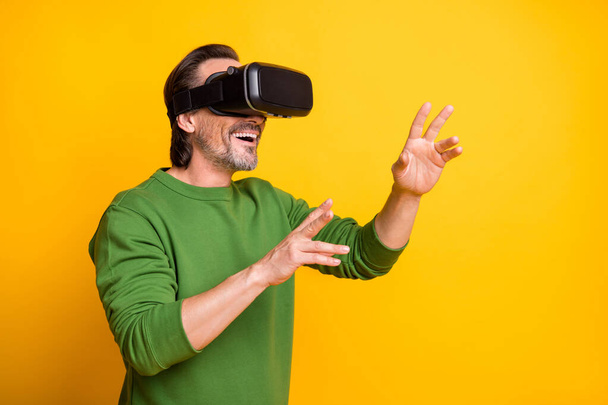 Photo portrait of bearded man playing game virtual reality wearing glasses smiling isolated on vivid yellow color background - Фото, зображення