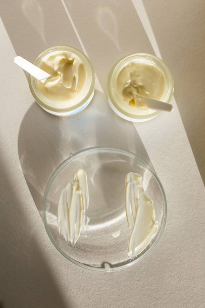 Cosmetische crème container met gezicht of lichaam crème op neutrale achtergrond - Foto, afbeelding