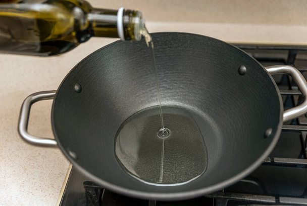 Pilaf de cuisson dans un chaudron, une recette pour le vrai pilaf. Huile de pépins de raisin pour la cuisson du pilaf, verser l'huile dans un chaudron, une casserole, avant la cuisson. - Photo, image