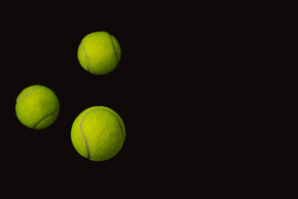 Três bolas de tênis voando em um fundo preto com espaço de cópia - Foto, Imagem