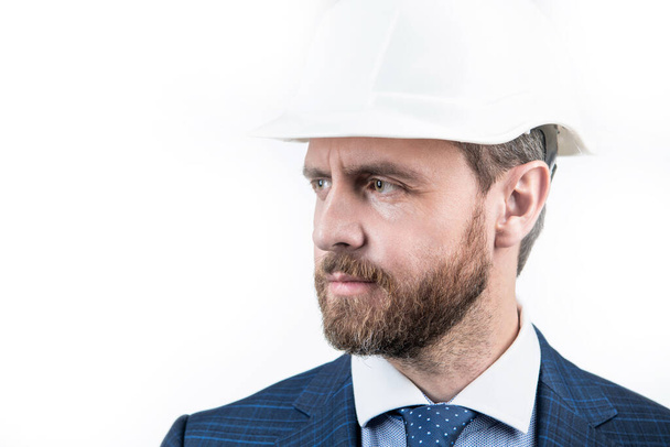 successful man looking away. entrepreneur in protective helmet. chief architect engineer. professional engineer in hardhat. copy space confident businessman in suit isolated on white. safety business. - Фото, изображение