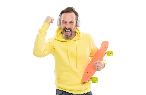 happy mature man skateboarder with beard in hoody listen music wearing headphones hold penny skateboard isolated on white, skateboard hobby. - 写真・画像