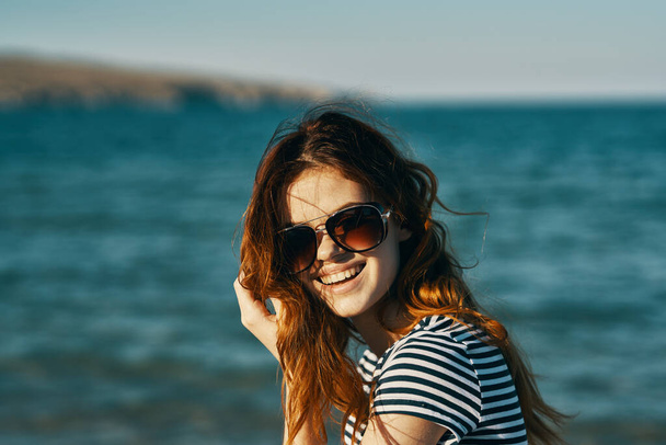 海の近くの山の中のサングラスの赤い髪の女性の肖像画と笑顔旅行観光 - 写真・画像