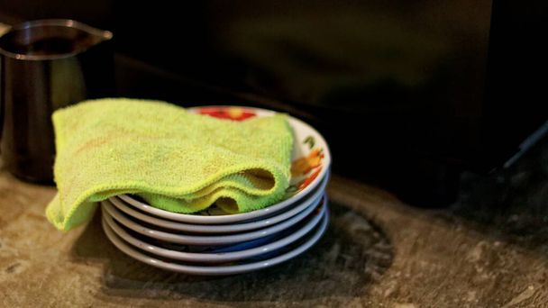 Zielona serwetka używana do czyszczenia spodka z kurzu, dzięki czemu produkt pozostaje czysty. - Zdjęcie, obraz