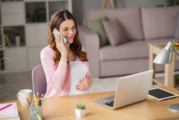 Portret van aantrekkelijke vrolijke zwangere meisje thuisblijven met behulp van laptop werken op afstand bellen klant praten huis binnen - Foto, afbeelding
