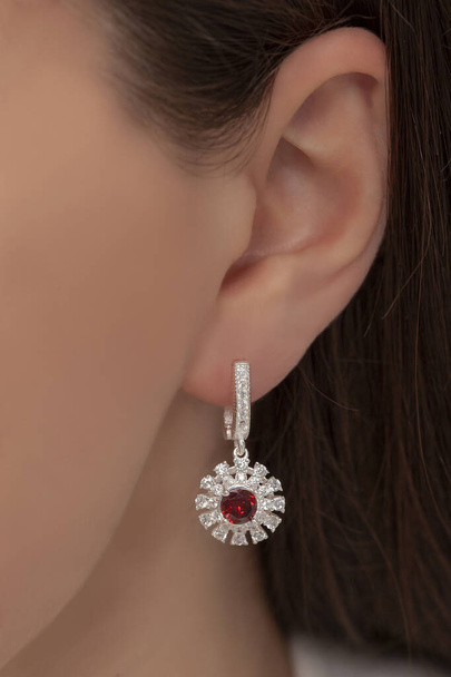 Silberne Ohrhänger, die am Ohr einer gepflegten Dame befestigt sind. Schmuckbild, das im E-Commerce-Verkauf verwendet werden kann. - Foto, Bild