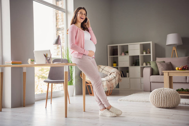 Full length body size profile side view of attractive cheerful pregnant girl staying home calling friend discussing in flat house indoors - Фото, зображення