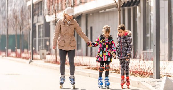 mother teaches daughter to roller skate - Photo, Image
