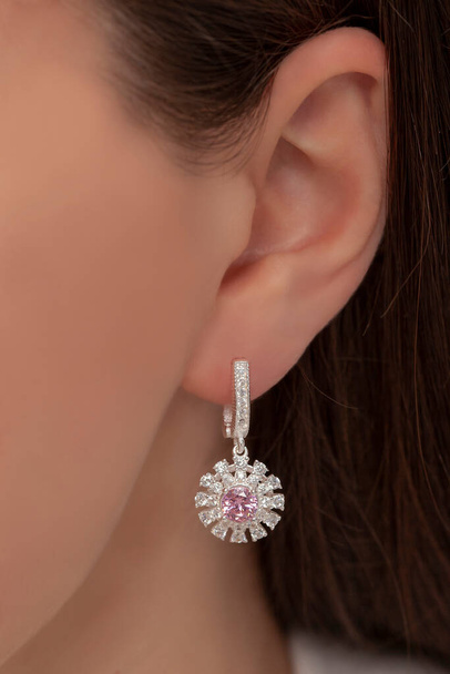 Brincos de prata pendurados na orelha de uma senhora. Imagem de jóias que pode ser usado em vendas de e-commerce. - Foto, Imagem
