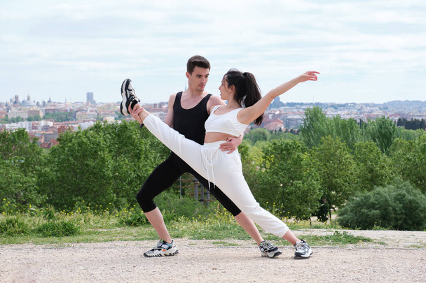 Młoda para ćwicząca taniec uliczny, balet, kroki taneczne, ruchy w parku. - Zdjęcie, obraz