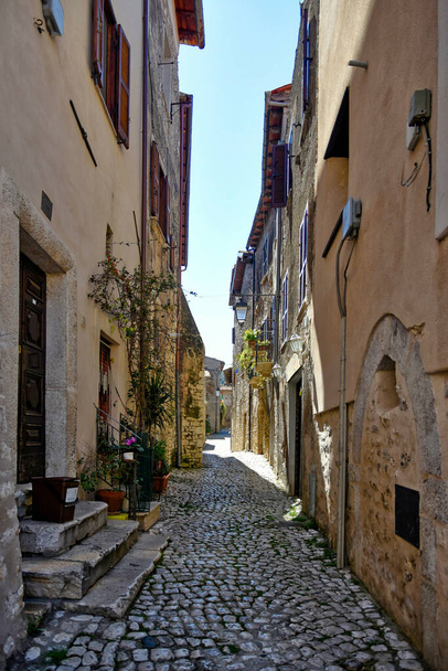 Sermoneta, Olaszország, 05 / 10 / 2021. Egy utca a régi középkori kőépületek között a történelmi városban. - Fotó, kép