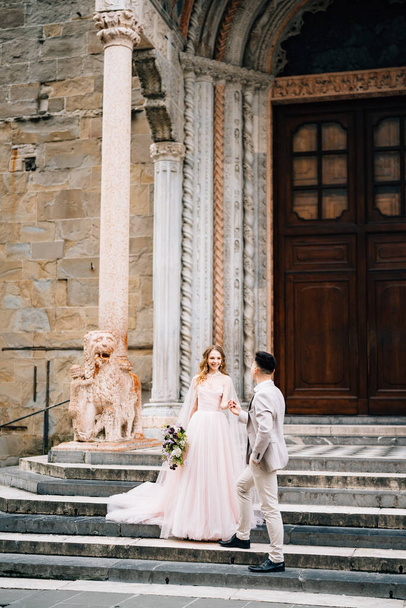 Bride and groom stand holding hands on the steps at the entrance to the Basilica of Santa Maria Maggiore in Rome - Zdjęcie, obraz
