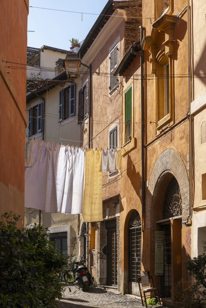 Trastevere, Rooma Tiberin rannalla, kuuluisa paikallisista pizzerioista ja yöelämästä, jossa roomalaiset tapaavat. Tyypillisellä roomalaisella kadulla roikkuvien vaatteiden viehättävä yksityiskohta. Rooma Italia. - Valokuva, kuva