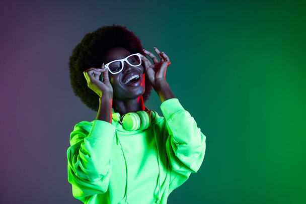 Portrait of cheerful dark skin person hands touch glasses toothy smile isolated on shine green background - 写真・画像
