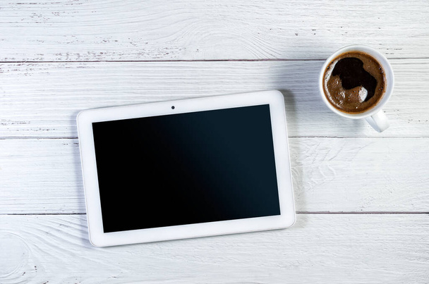 Tablet PC και κούπα καφέ σε λευκή ξύλινη επιφάνεια. Διαδρομή αποκοπής για χώρο αντιγραφής οθόνης - Φωτογραφία, εικόνα