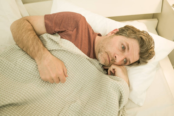 Man suffering depression - dramatic portrait at home of sad and depressed guy early 40s lying on bed having anxiety problem feeling desperate and broken heart  - Photo, image