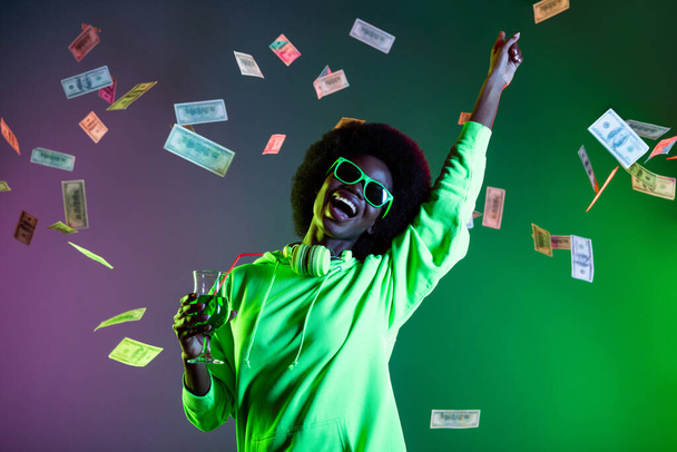 Portrait of crazy excited dark skin lady raise hand point finger falling money isolated on green colorful background - Fotografie, Obrázek