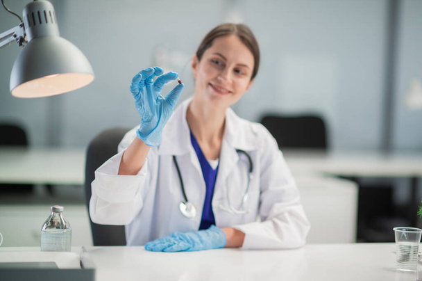 新しい抗ウイルス薬の発表.女性医師は患者への治療を規定し、薬のカプセルを手に持っている - 写真・画像