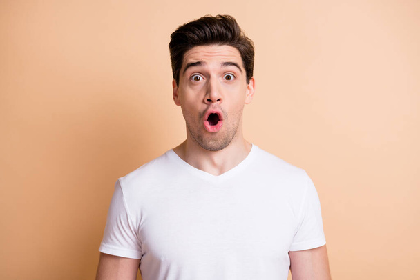 Photo of crazy amazed young man open mouth unbelievable information isolated on pastel beige color background - Photo, Image