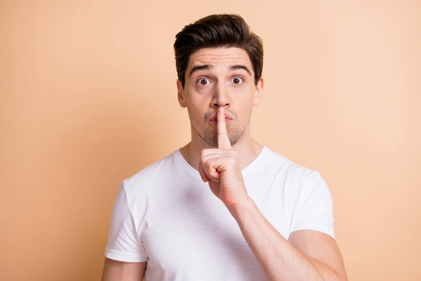 Photo of worried person finger covering lips do not tell look camera isolated on beige color background - 写真・画像