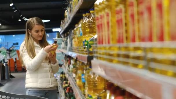 La niña compra aceite de oliva en el supermercado, productos naturales de origen vegetal.  - Metraje, vídeo