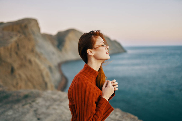 海側のビュー山の近くの赤いセーターの女性新鮮な空気 - 写真・画像