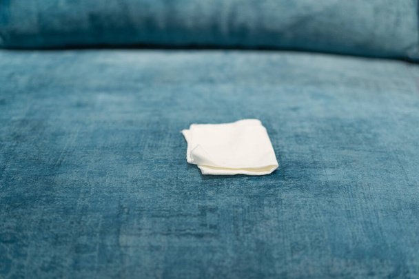 Γυναίκα καθαρίζει ένα μπλε καναπέ με λευκό πανί. Καθαρισμός καναπέ. Αφαίρεση λεκέδων. - Φωτογραφία, εικόνα