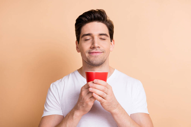 Photo of satisfied person arms hold coffee cup closed eyes nice smelling isolated on beige color background - Foto, afbeelding