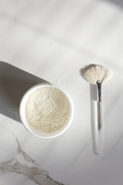 brosse de maquillage avec fond de teint en poudre isolé sur table en marbre blanc avec pot en poudre - Photo, image