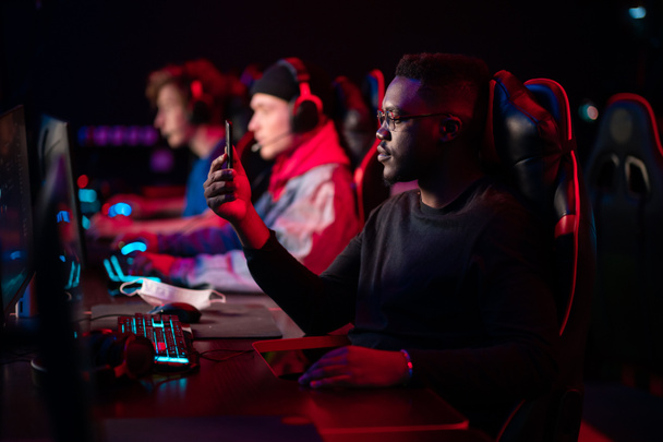 A multi-racial team of esports athletes conducts a training session before an online shooter tournament. Neon light. - Photo, Image