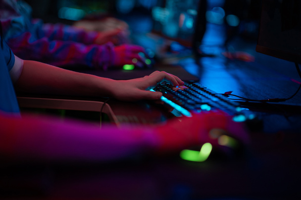 Τα χέρια ενός αρσενικού παίκτη κατά τη διάρκεια ενός τεταμένου παιχνιδιού, το πληκτρολόγιο και το ποντίκι είναι ορατά. - Φωτογραφία, εικόνα