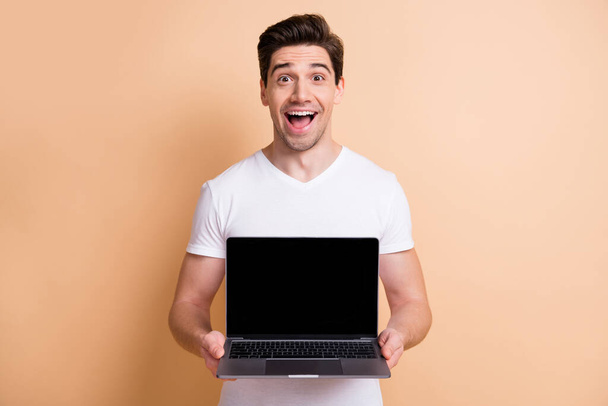 Photo of impressed handsome person open mouth hold netbook showing display isolated on beige color background - Fotografie, Obrázek
