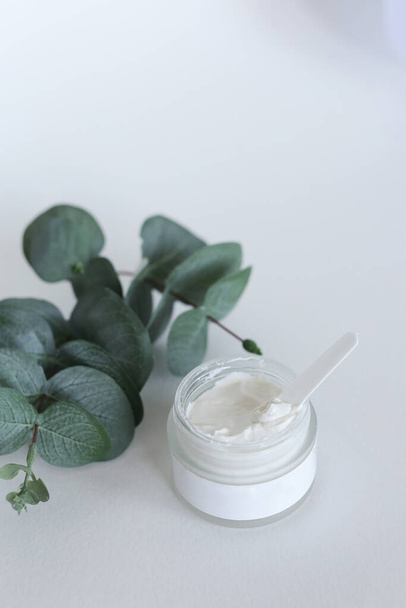 Crème cosmétique hydratante à l'eucalyptus se tient sur fond neutre avec éclaboussure de lait - Photo, image