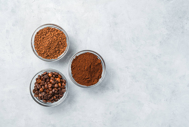 Drie soorten koffie: granulaat, gemalen graan op een grijze achtergrond met ruimte om te kopiëren. Bovenaanzicht, horizontaal. - Foto, afbeelding