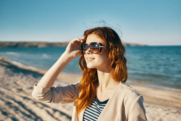 šťastná žena na pláži v blízkosti moře v horách brýle na tváři rudé vlasy model krajiny - Fotografie, Obrázek