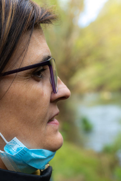 Вибірковий фокус портрета жінки середнього віку в окулярах, що дивляться на природу під час заходу сонця з копіювальним простором
. - Фото, зображення