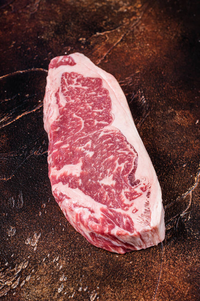 Syrový steak z New Yorku nebo striptýz na řeznickém stole. Tmavé pozadí. Horní pohled - Fotografie, Obrázek